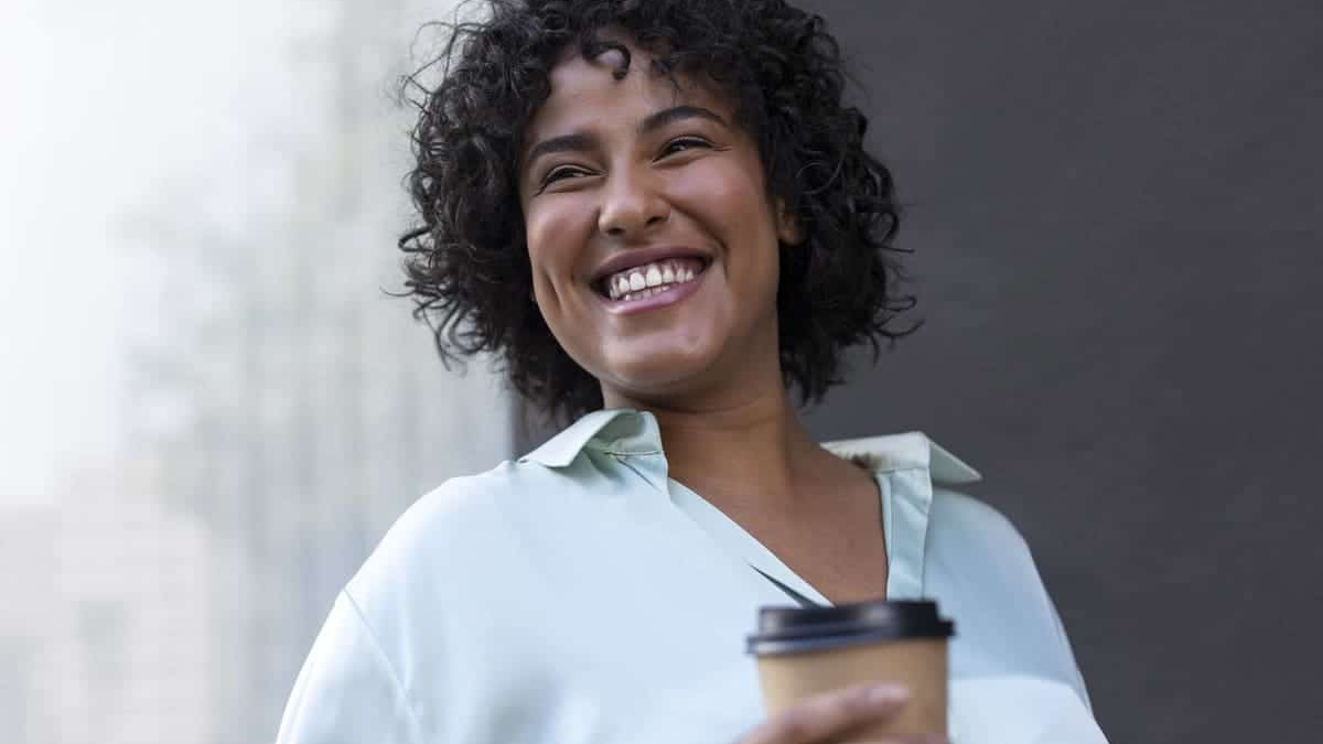 budget sparena life you love starts with simple moments, a smiling woman holding a takeaway coffee, enjoying a calm break in an urban setting
