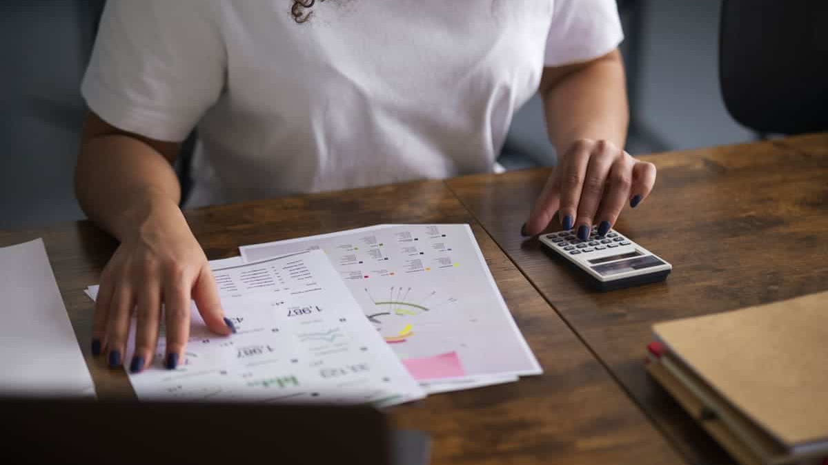 Finanzielle finances analysis with a person reviewing financial charts and documents on a desk while using a calculator to plan expenses and budgets