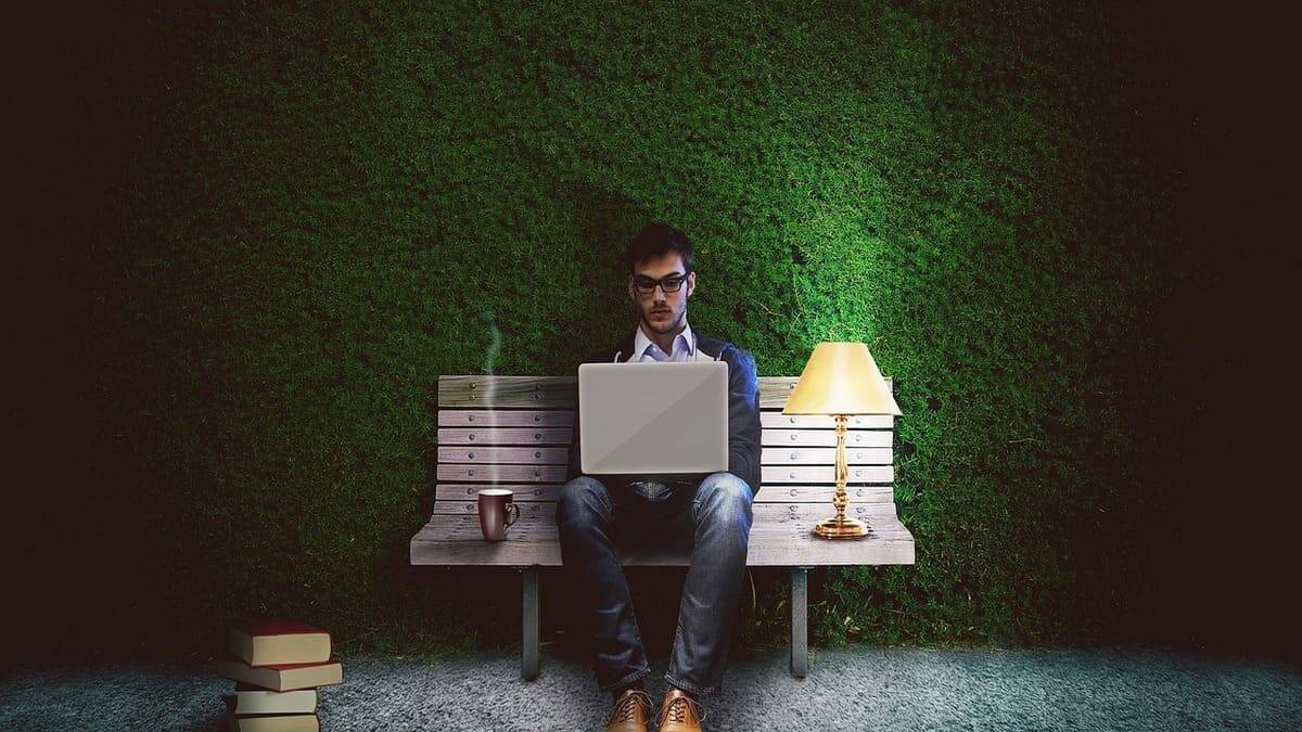 Person organizing finances at a kitchen table with a notebook and coffee cup