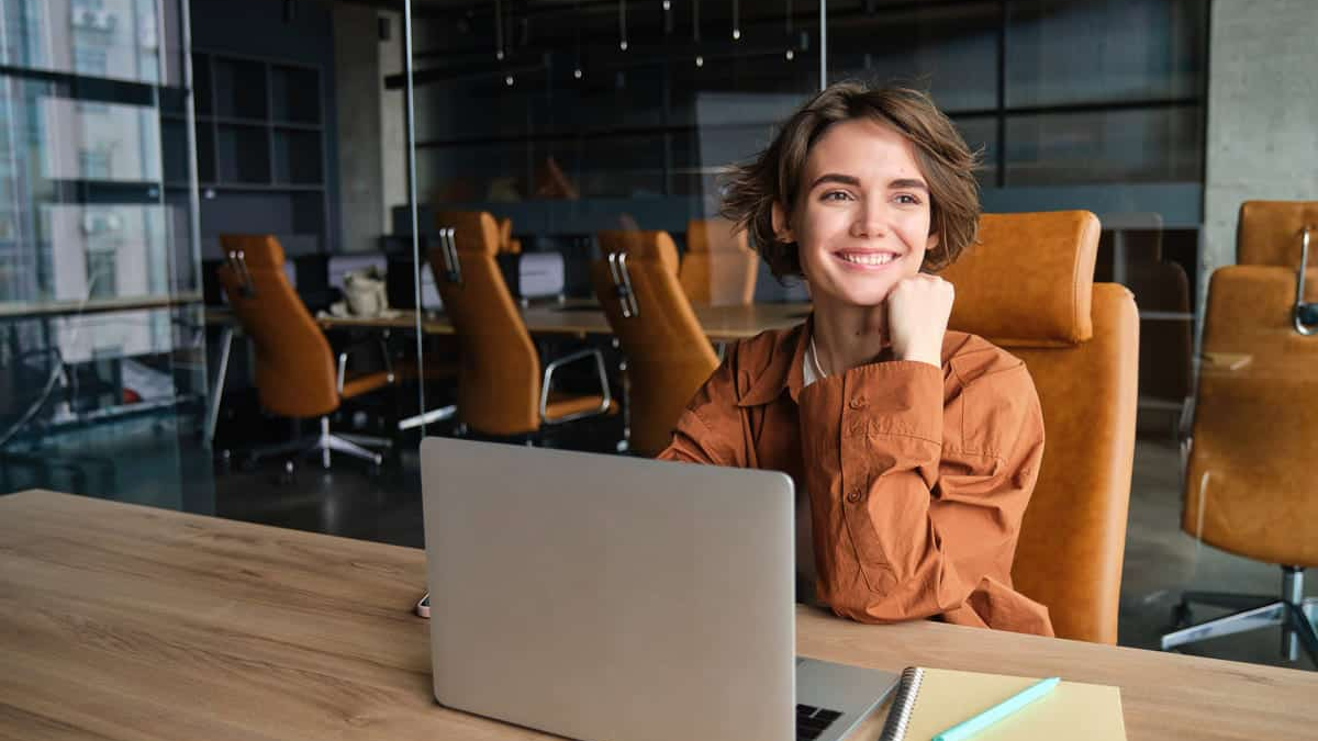 Karriere career roadmap professional smiling while working on a laptop at a modern office desk, planning long-term career and income growth