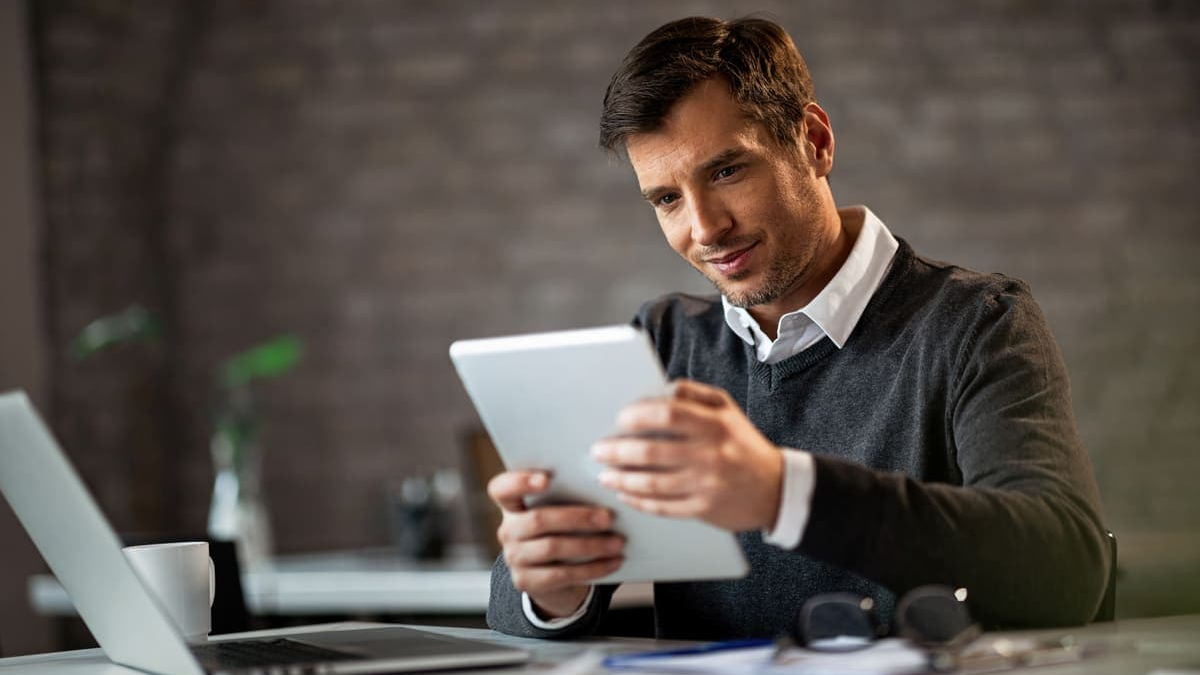 finanzen investieren analysis at the office with a professional reviewing financial data on a tablet beside a laptop and documents