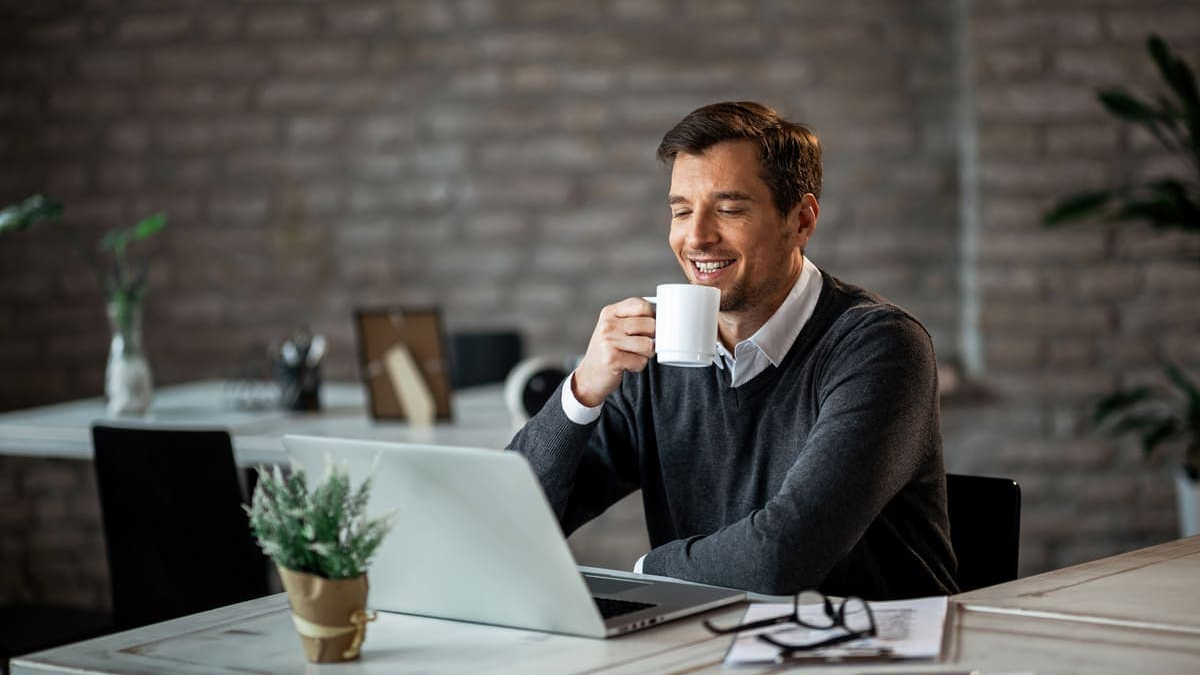 Schulden A focused man with glasses and a backpack sits at a wooden desk, diligently writing on a financial planning sheet with colorful sections, surrounded by a laptop