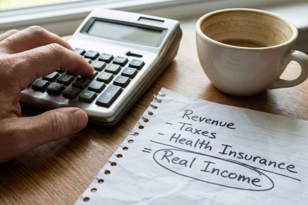 Close-up of a calculator and financial notes showing the calculation of freelance revenue minus taxes and expenses.