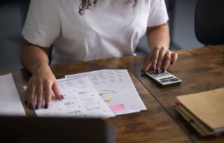finances analysis with a person reviewing financial charts and documents on a desk while using a calculator to plan expenses and budgets